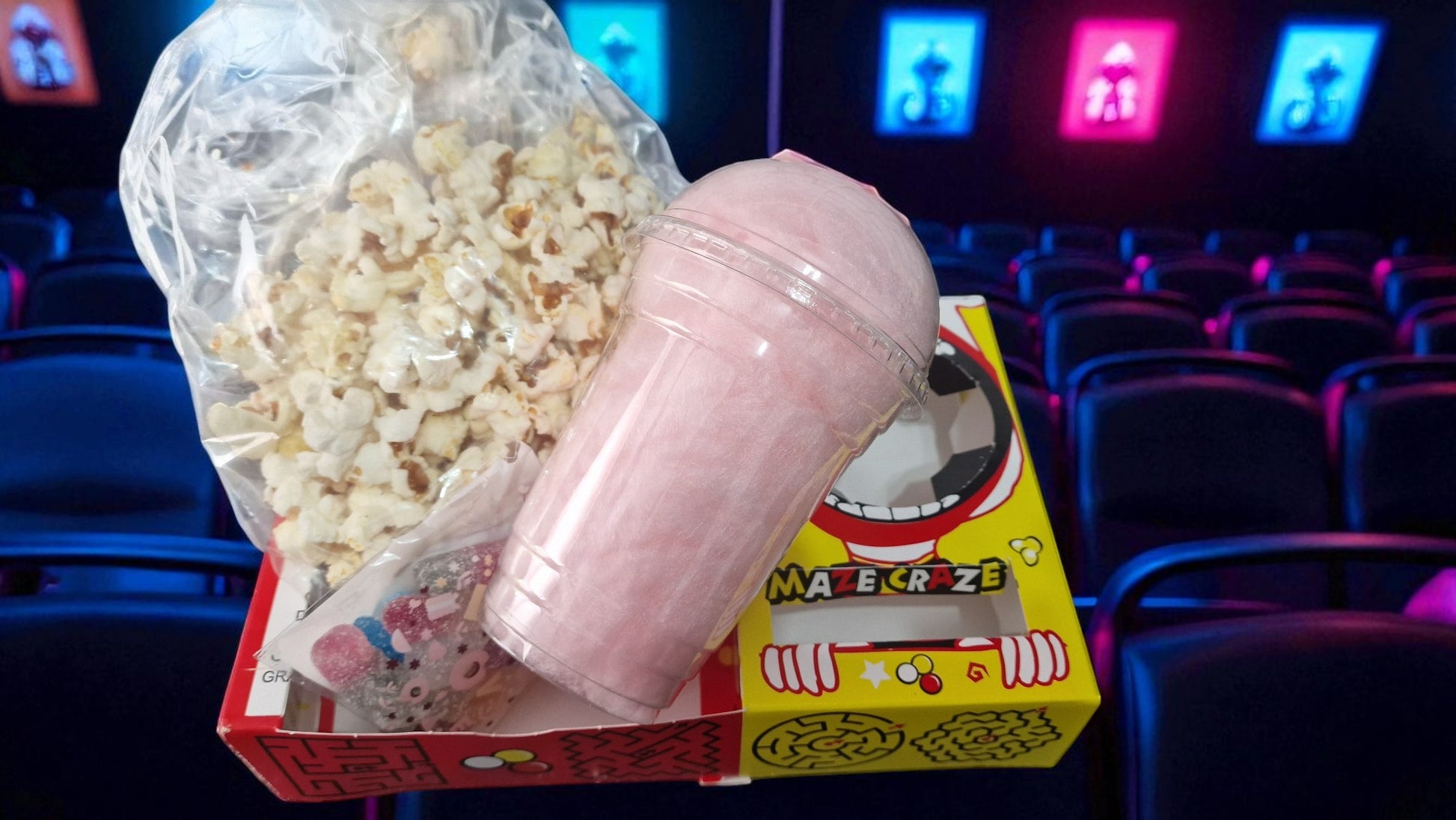 Popcorn and cotton candy in a theater setting with movie screens in the background