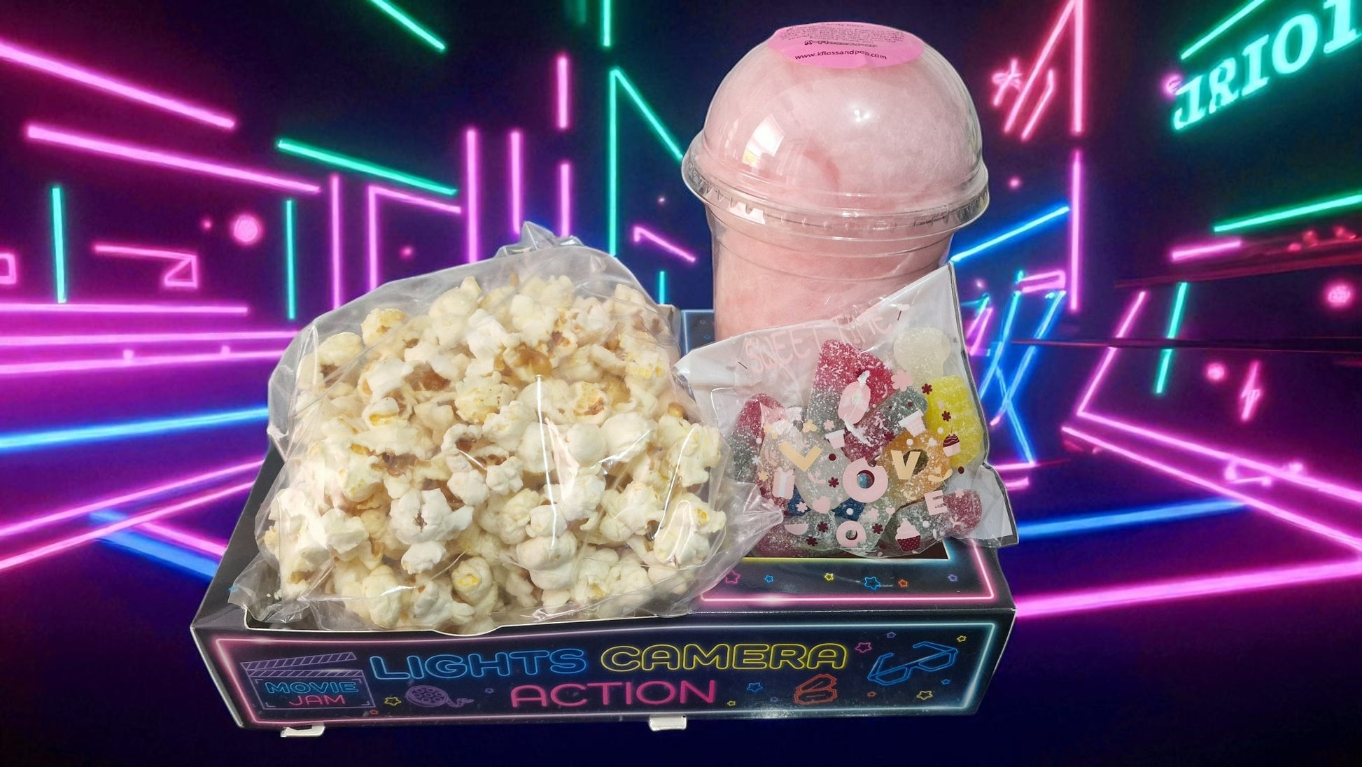Popcorn and cotton candy on a 'Lights Camera Action' stand with a neon background