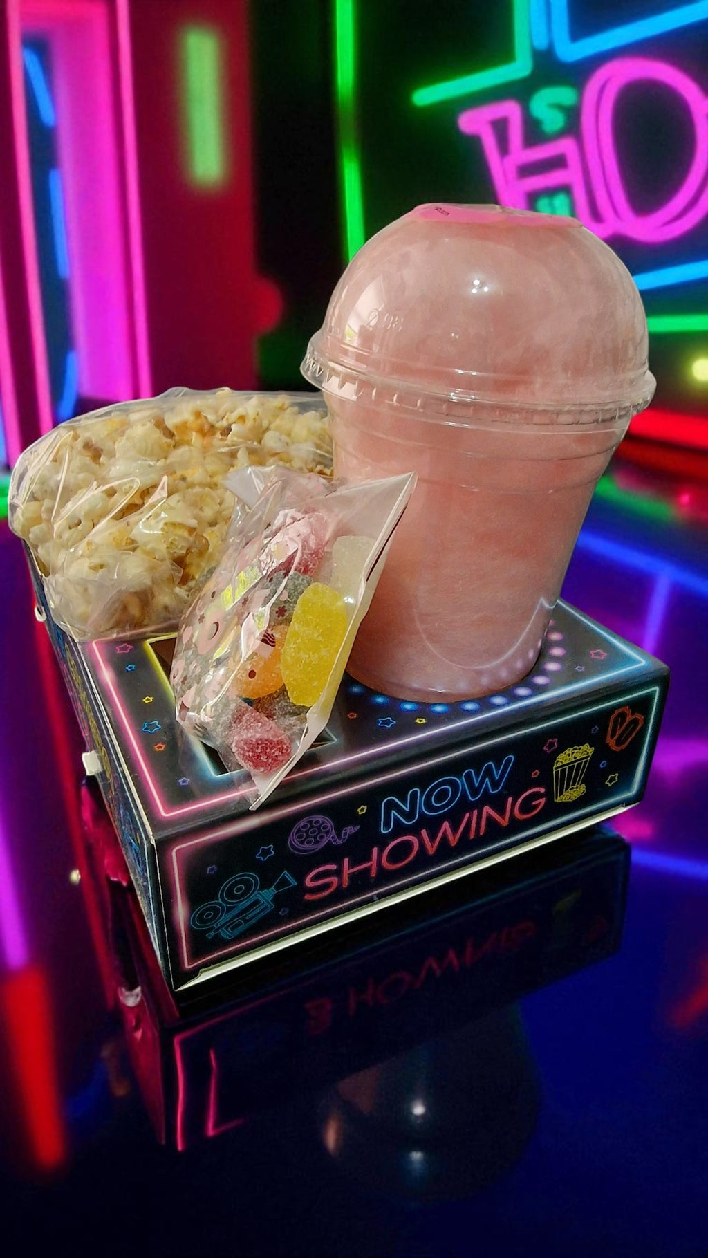 Pink cotton candy machine with popcorn and gummy worms on a colorful background