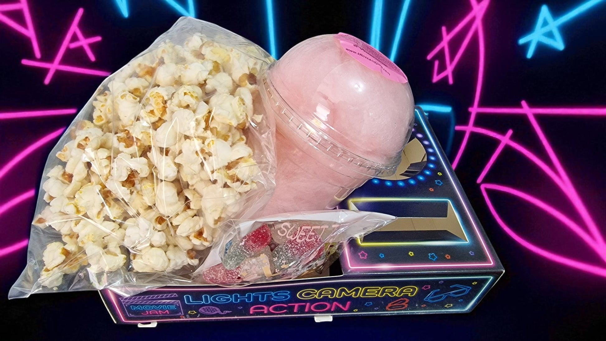 Popcorn and a pink object on a toy camera with neon lights in the background