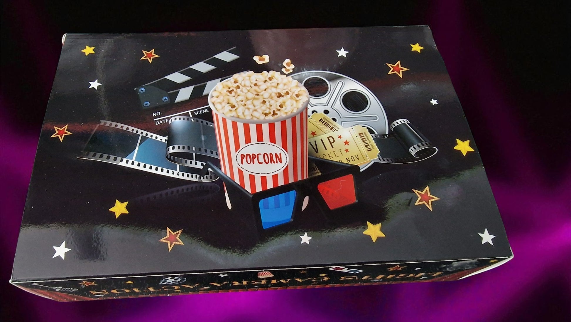Movie-themed box with popcorn, clapperboard, and filmstrip on a dark background