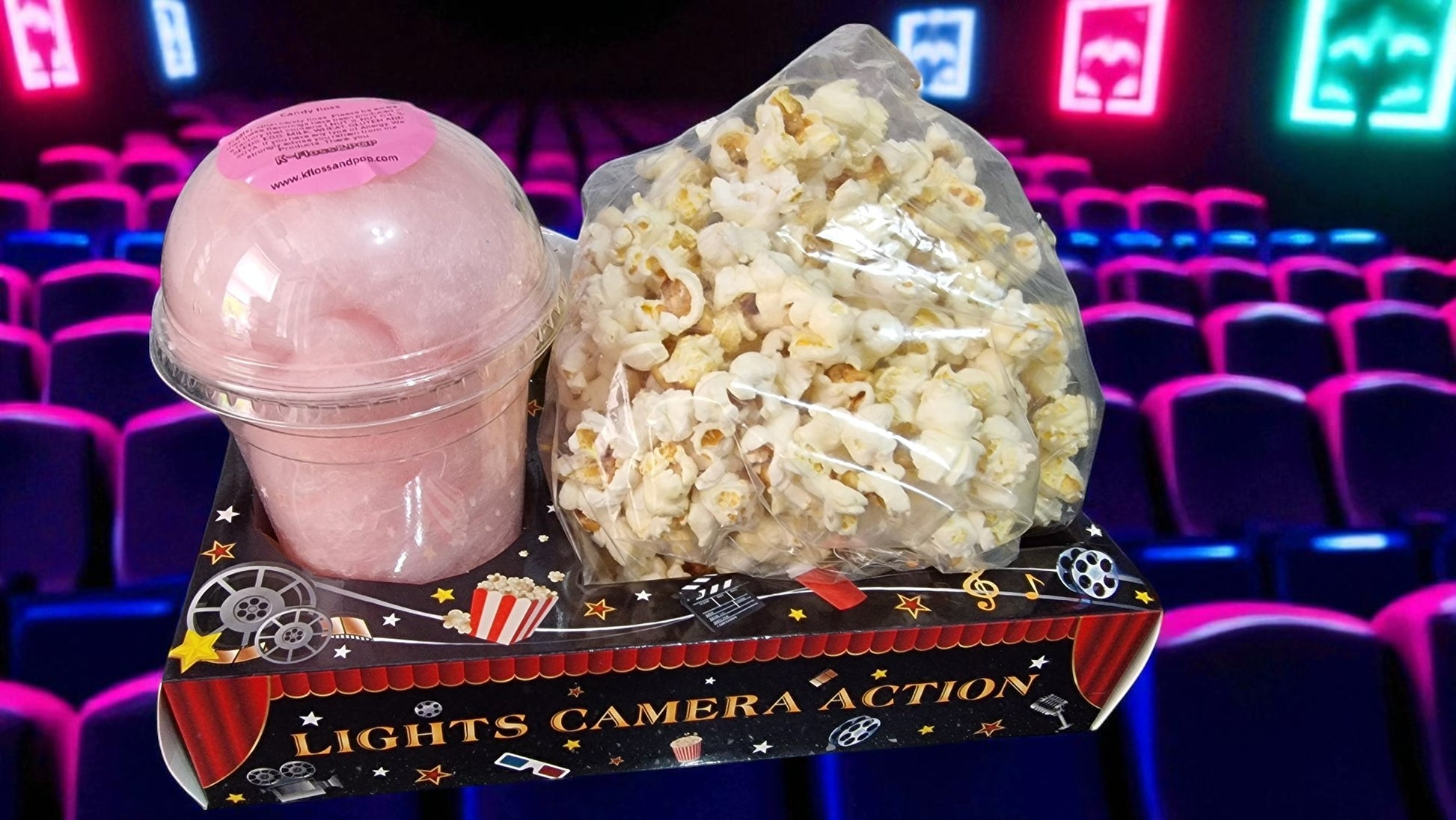 Popcorn and a pink popcorn bucket on a 'Lights Camera Action' tray with movie theater seats in the background