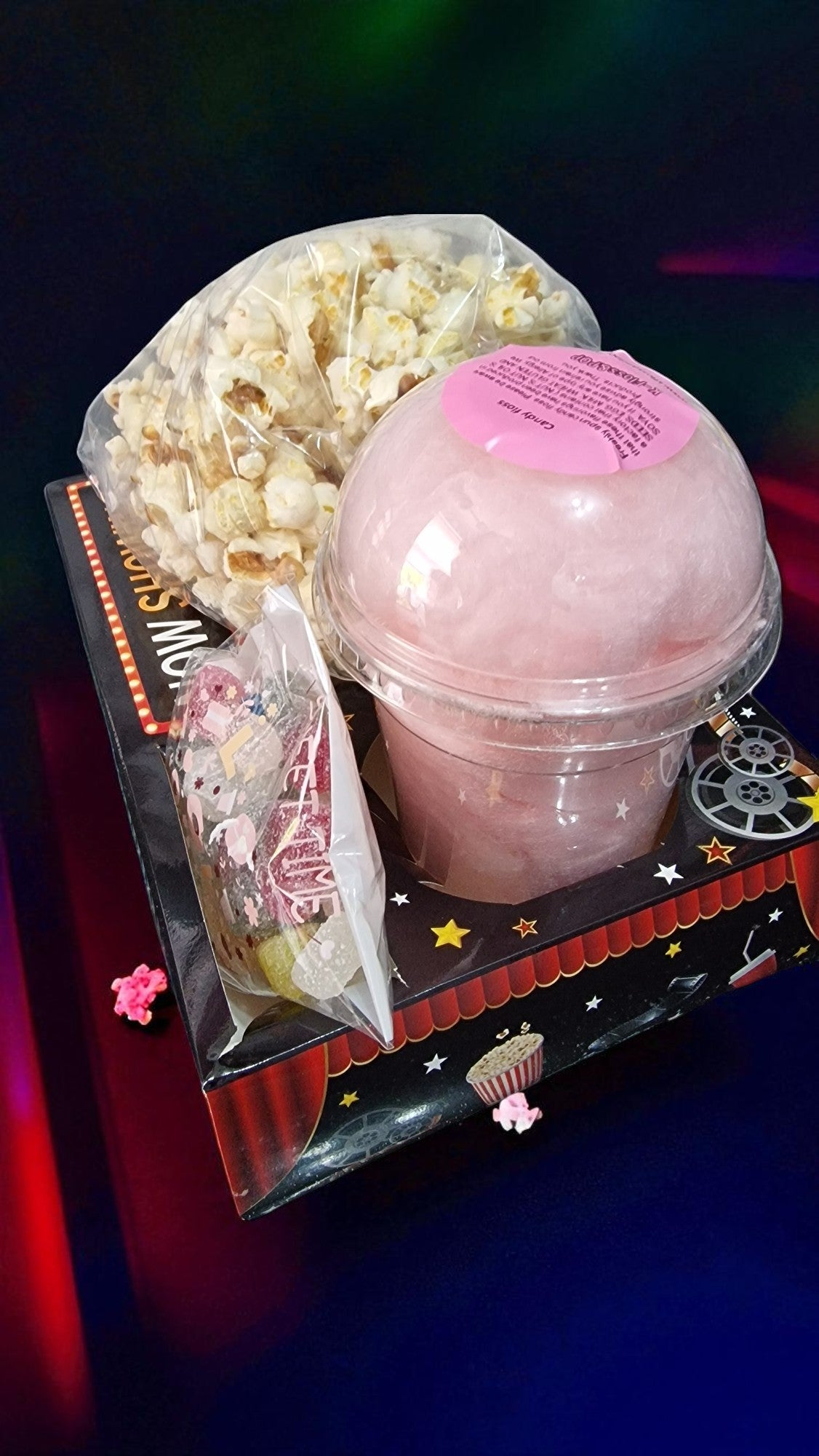Pink bath bomb with a bag of popcorn and a small toy on a decorative stand.