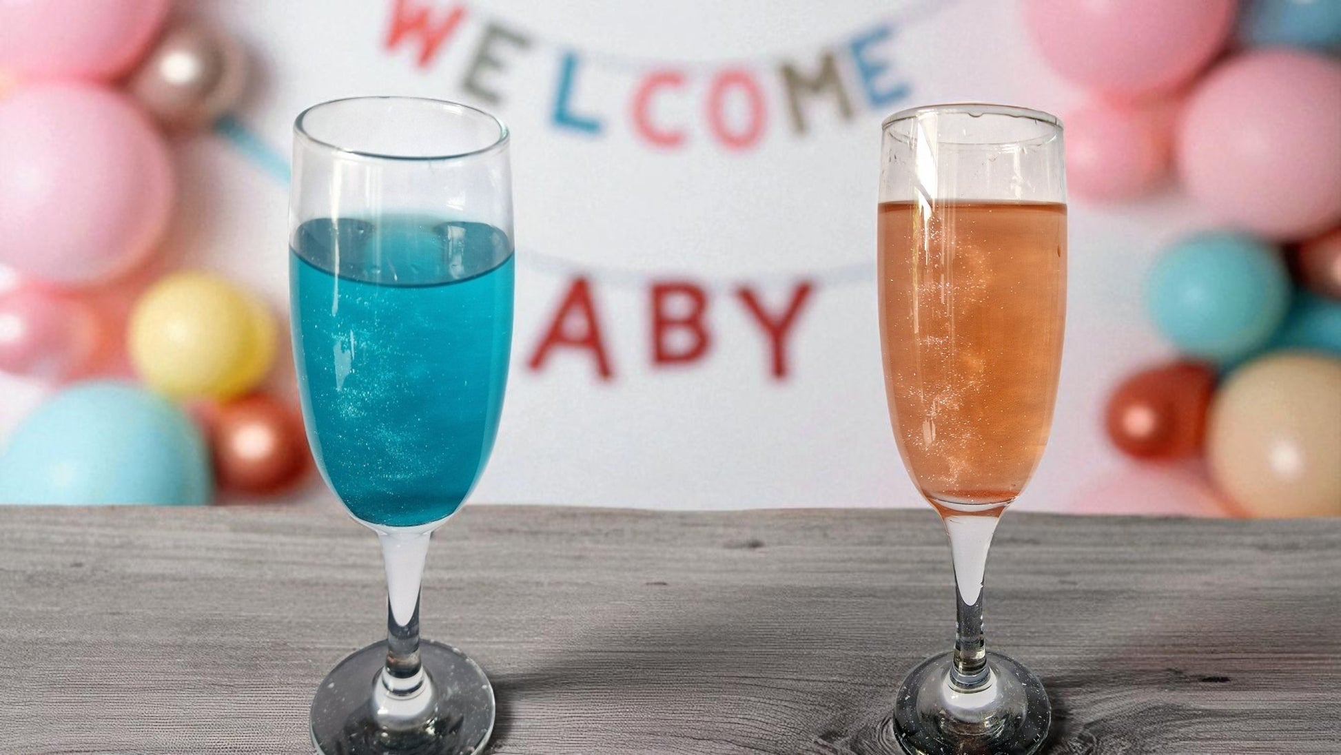 Two glasses of sparkling drinks—one blue, one pink—on a table with two white shimmer candy floss drink bombs in gold domes, perfect for gender reveal parties