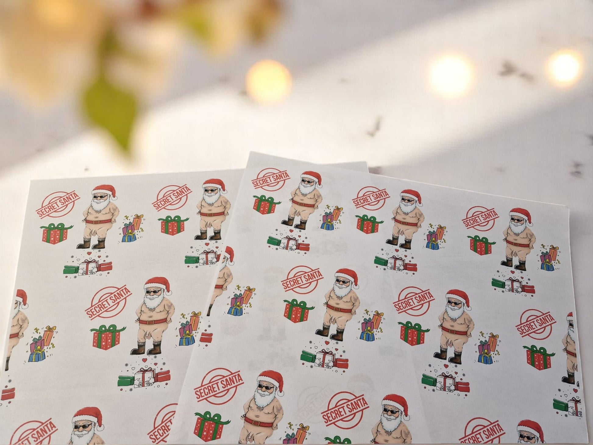 Cheeky Secret Santa Christmas wrapping paper featuring a cartoon naked Santa with gifts, Secret Santa stamps, and colourful presents on white A3 sheets