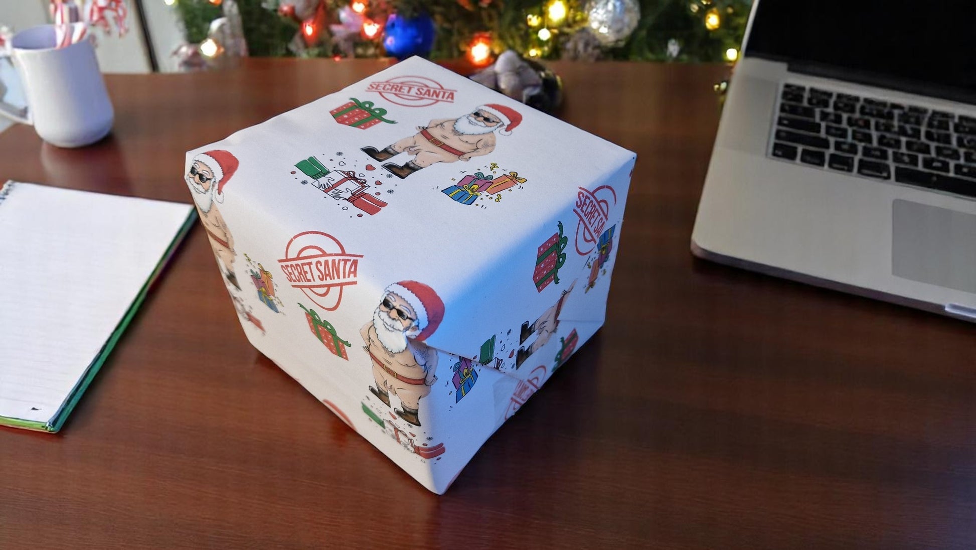 Cheeky Secret Santa Christmas wrapping paper featuring a cartoon naked Santa with gifts, Secret Santa stamps, and colourful presents on white A3 sheets