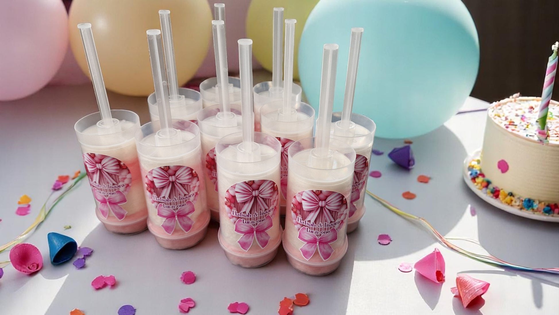 Ten personalised candy floss push pops in clear tubes with custom labels, displayed on a party table with colourful decorations—perfect for kids or adults