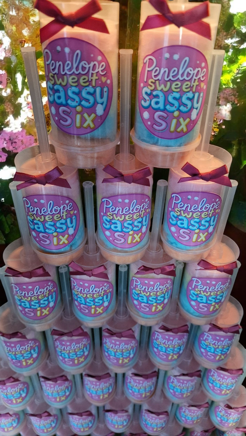 Ten personalised candy floss push pops in clear tubes with custom labels, displayed on a party table with colourful decorations—perfect for kids or adults