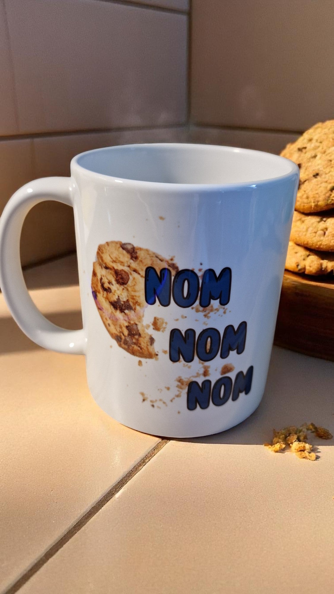 Mug with 'Nom Nom Nom' text and cookie碎屑 on a kitchen counter