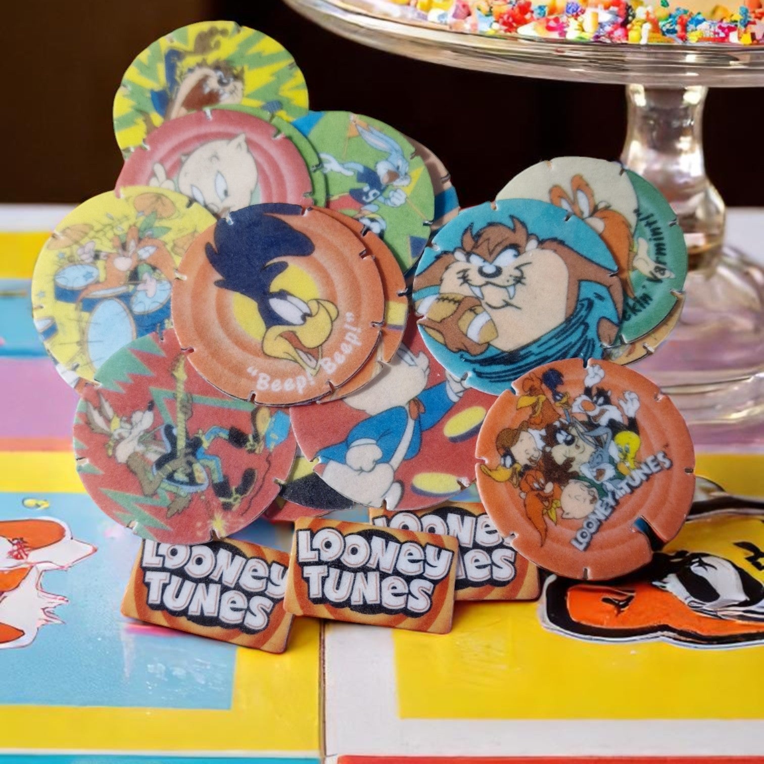 Colorful Looney Tunes-themed cookies on a table with a cake stand in the background.