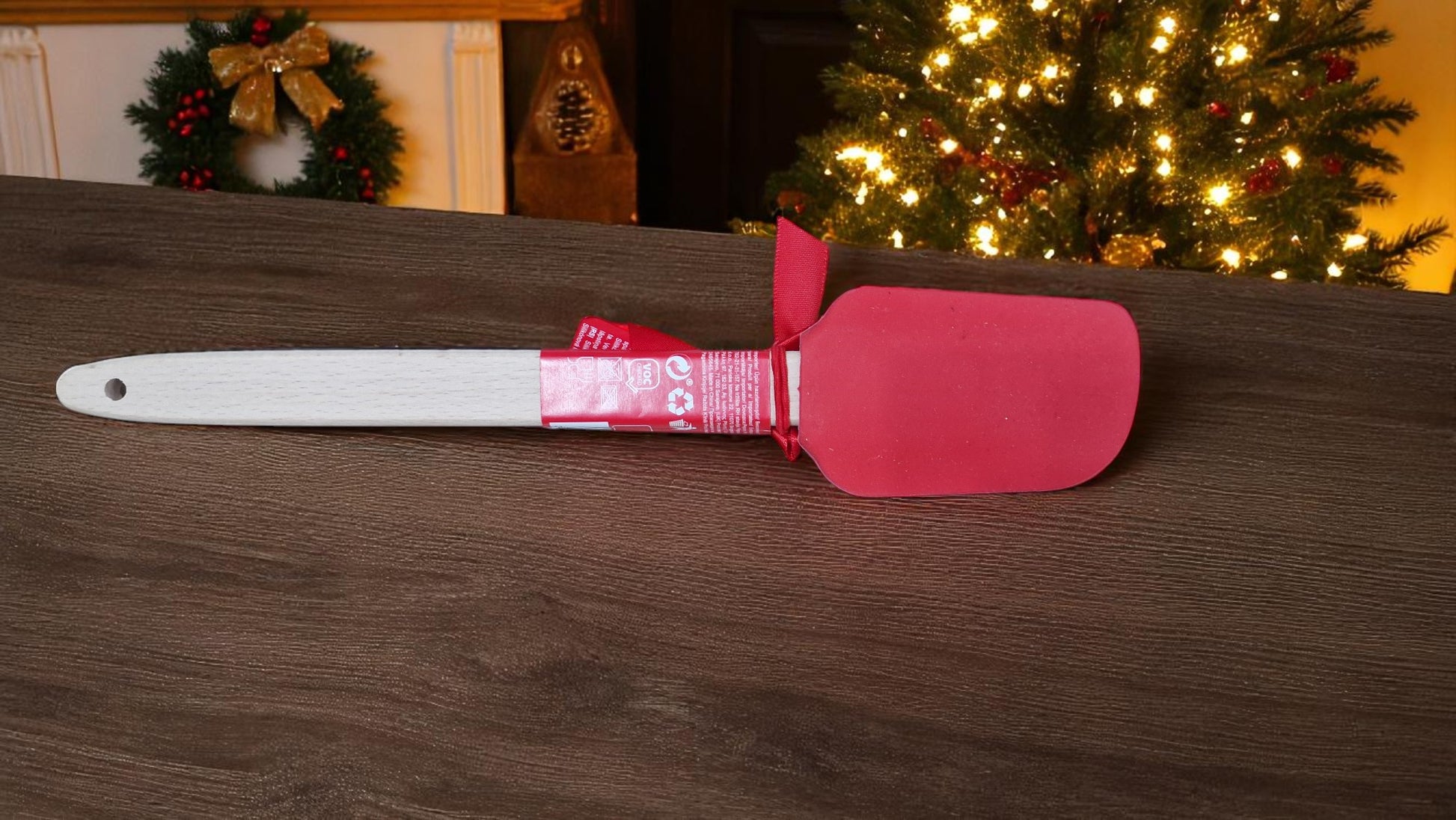 Red and white Christmas silicone spatula personalised with a name, surrounded by festive cookies and holiday decorations.