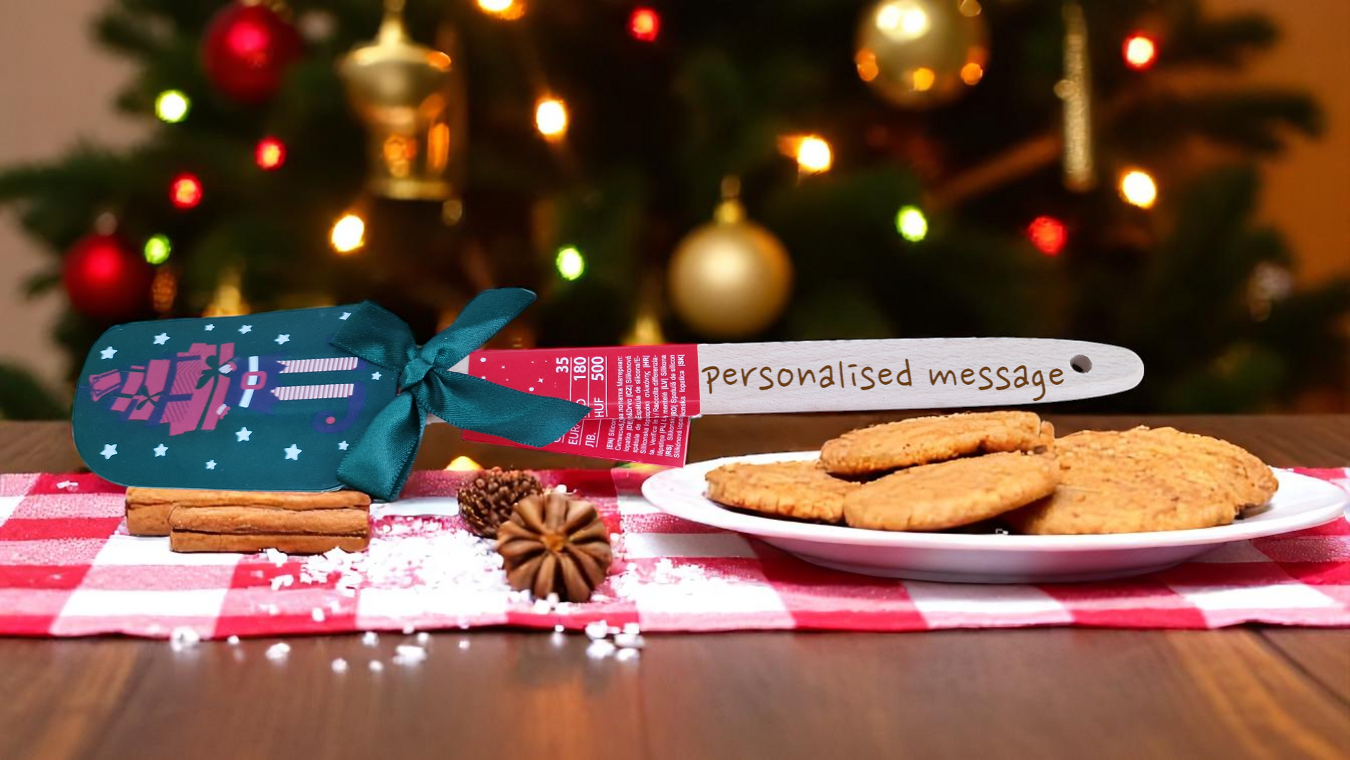 Red and white Christmas silicone spatula personalised with a name, surrounded by festive cookies and holiday decorations.