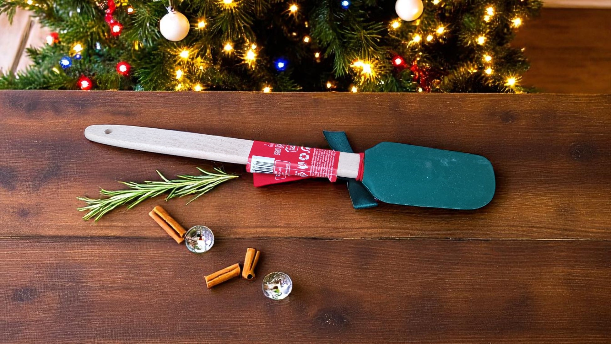 Red and white Christmas silicone spatula personalised with a name, surrounded by festive cookies and holiday decorations.