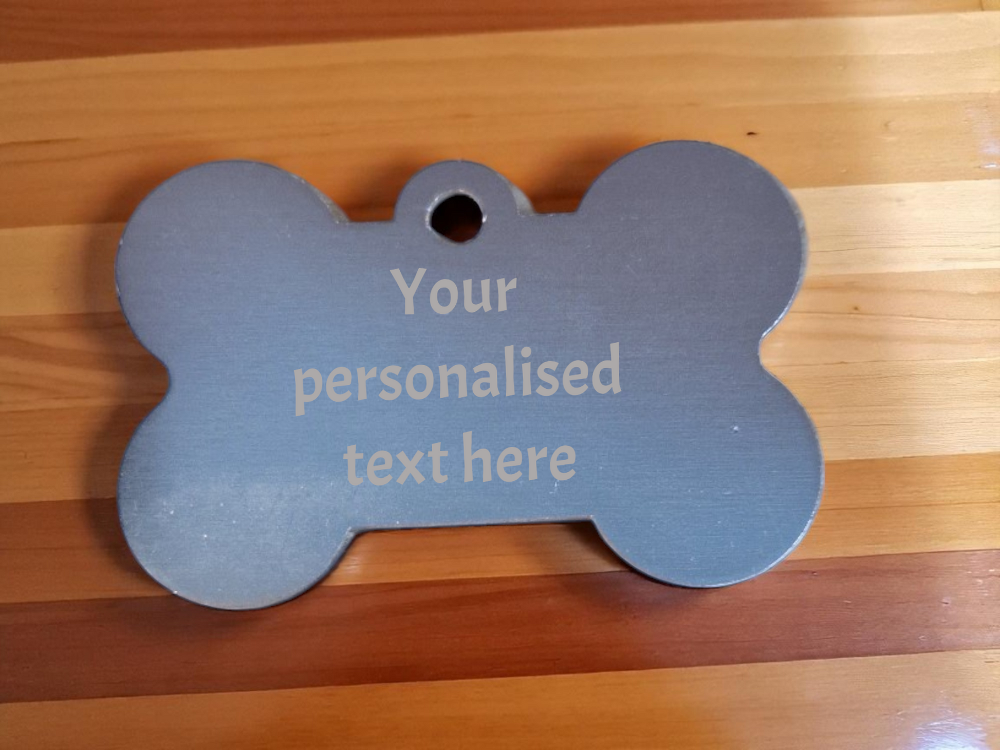 Bone-shaped personalized pet tag on a wooden surface