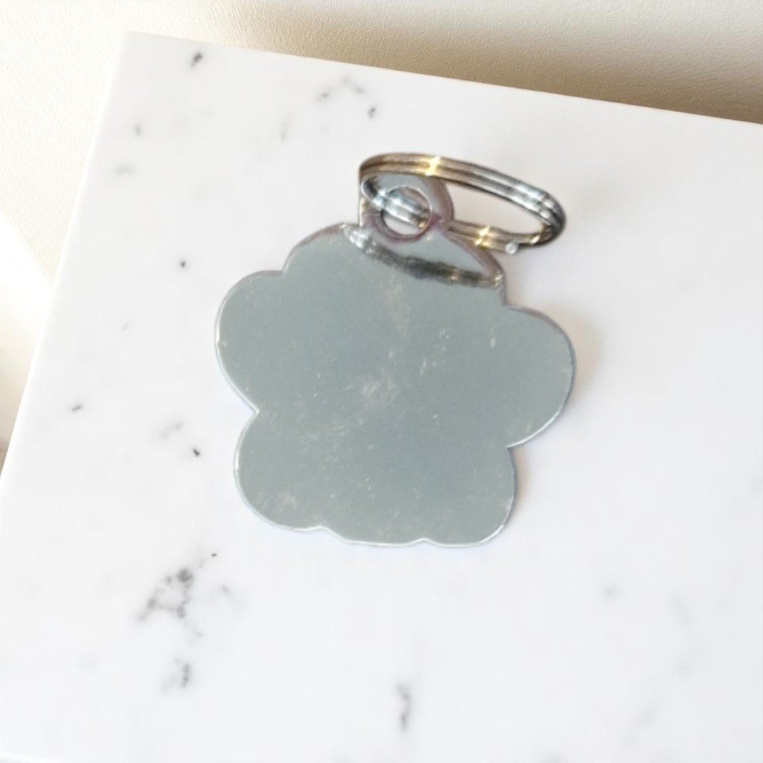 Metal paw-shaped keychain on a marble surface