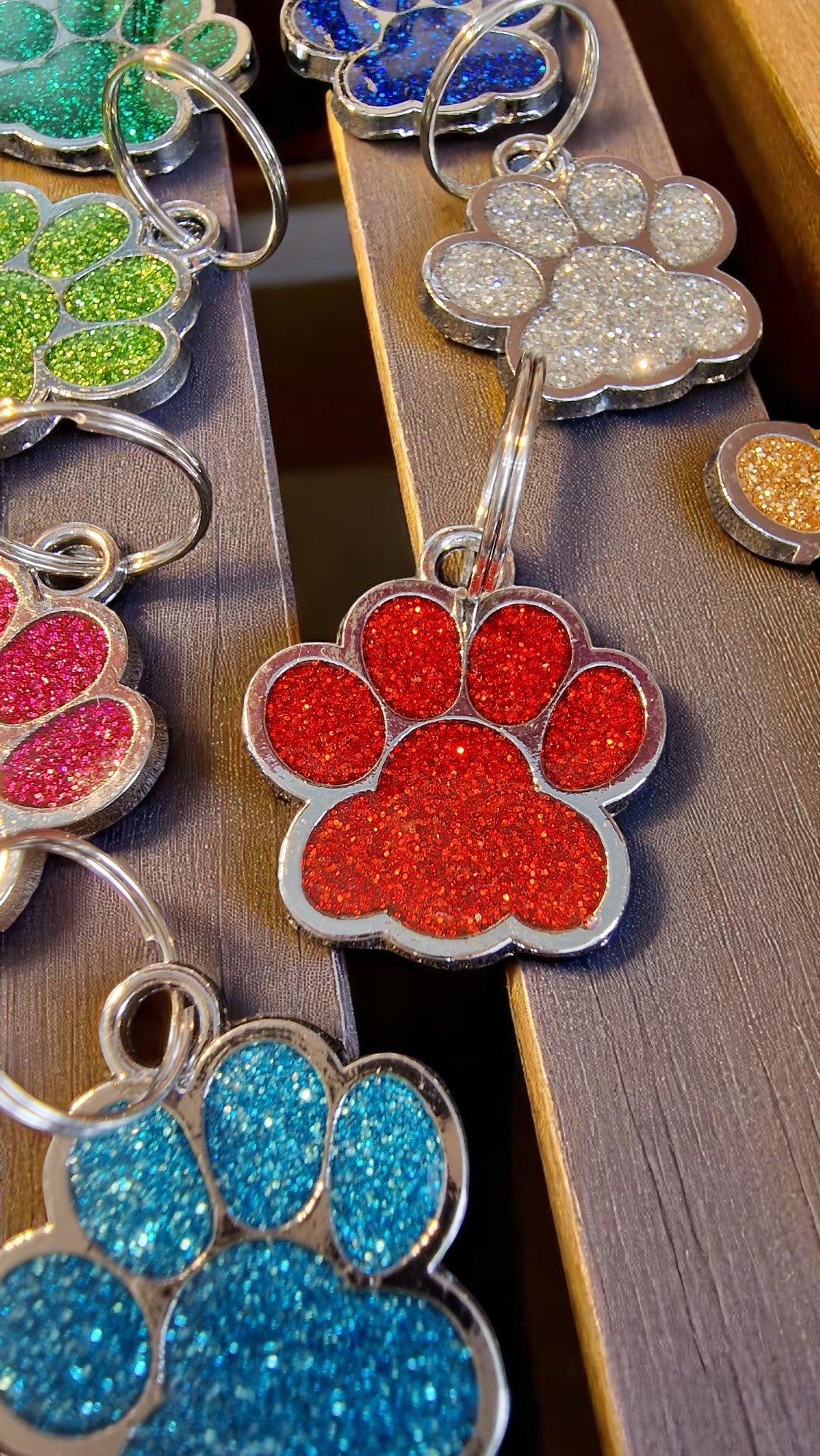 Colorful glittery paw-shaped keychains on a wooden surface