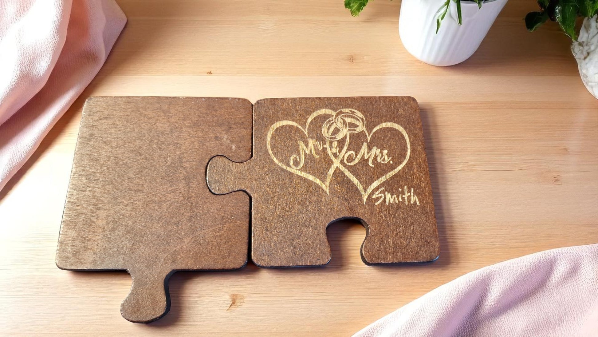 Set of two personalized jigsaw-style wooden coasters, 8x8 cm each, engraved with custom names and a heart design.