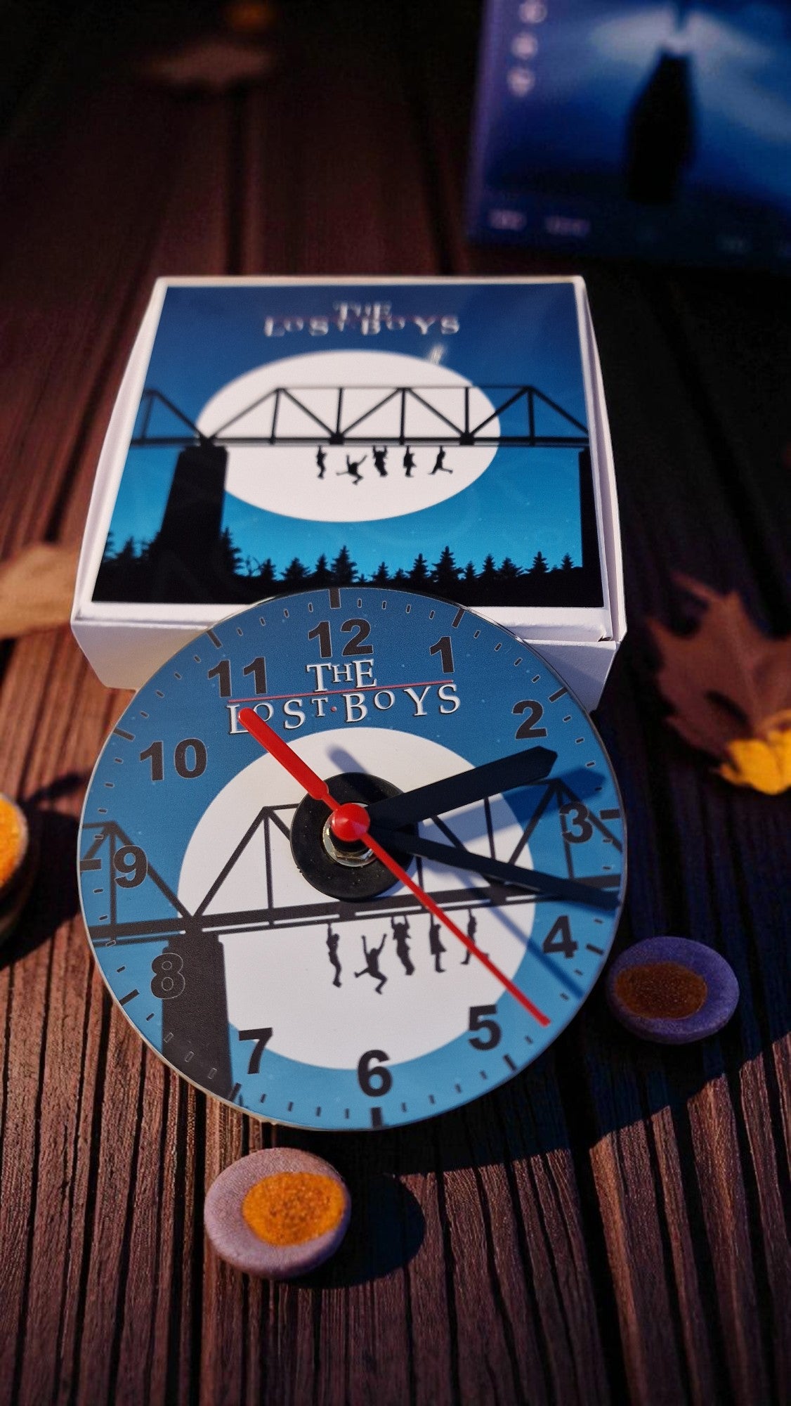 Circular clock with 'The Lost Boys' design on a wooden surface