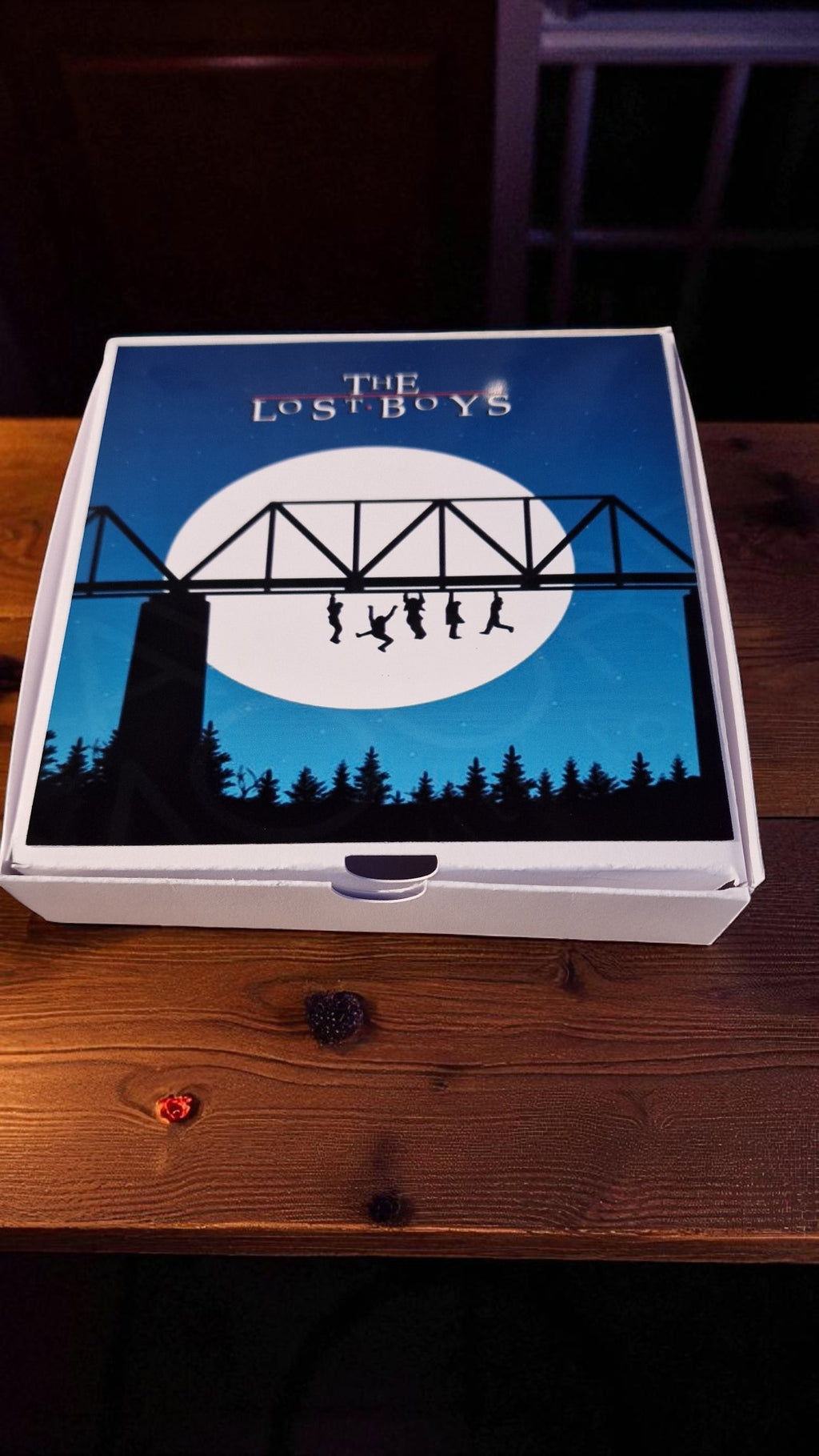 Board game box titled 'The Lost Boys' on a wooden surface