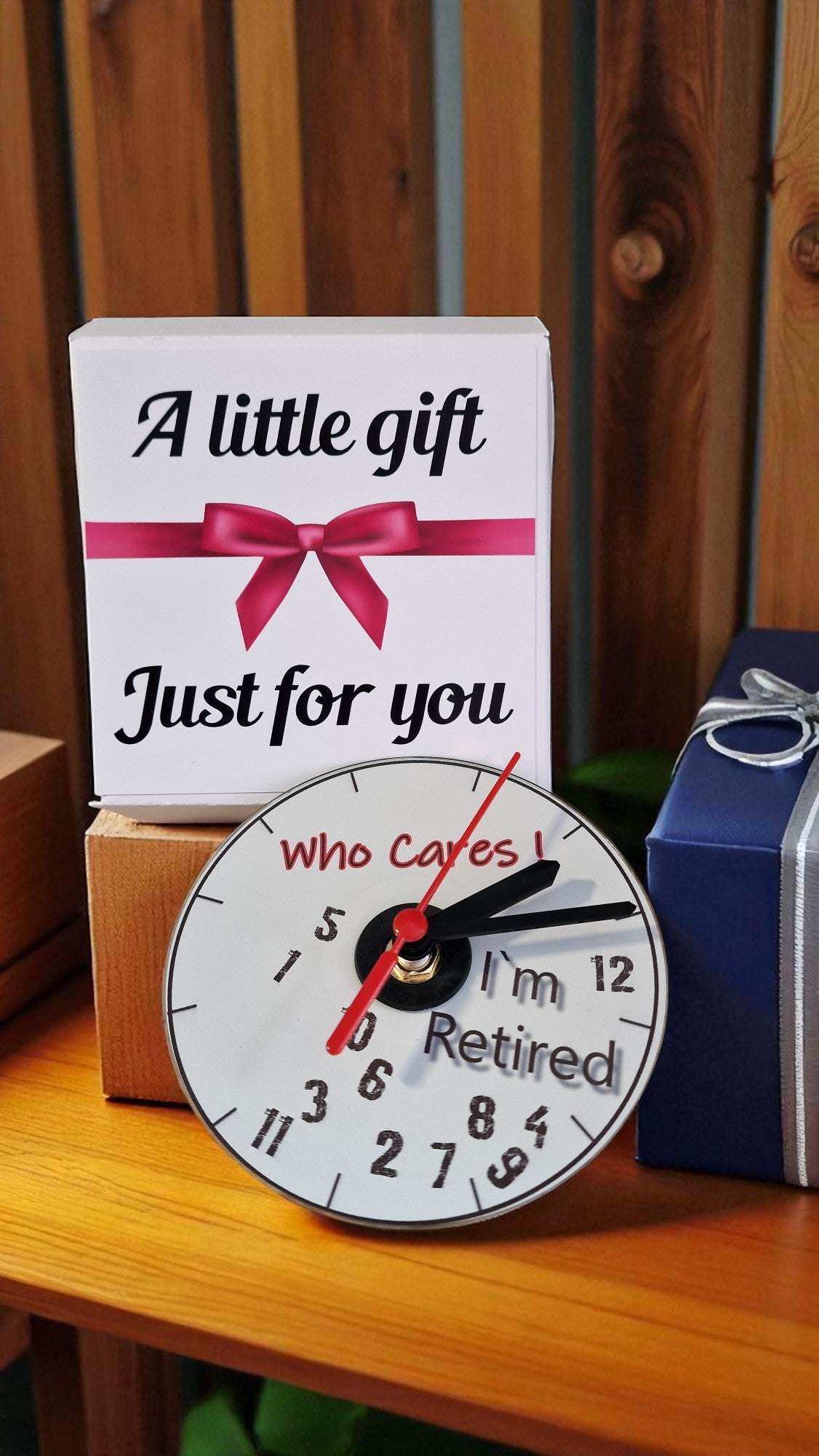 Clock with humorous message 'Who Cares I'm Retired' on a wooden surface with gift elements.