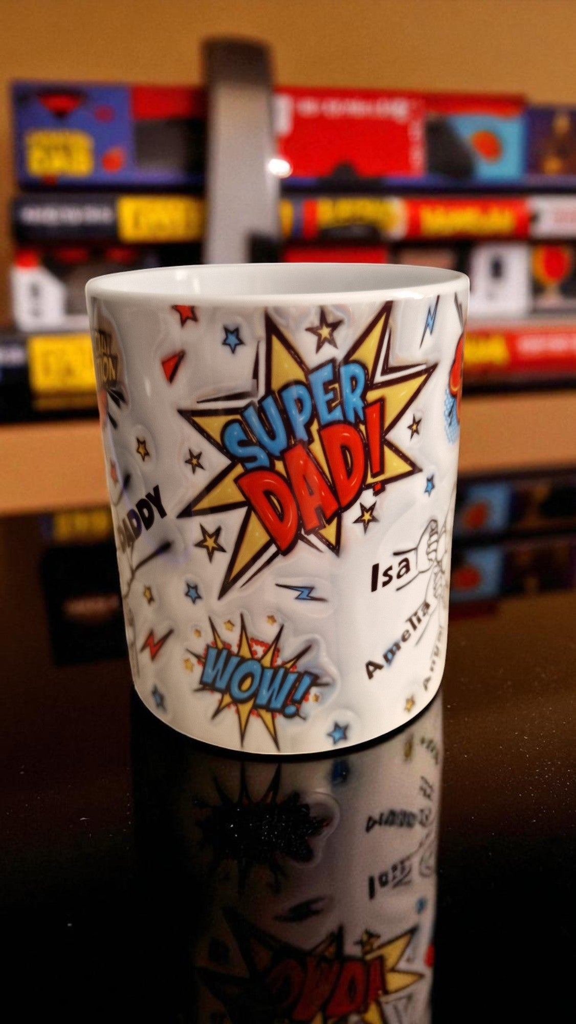 Mug with 'Super Dad!' design on a reflective surface with colorful boxes in the background