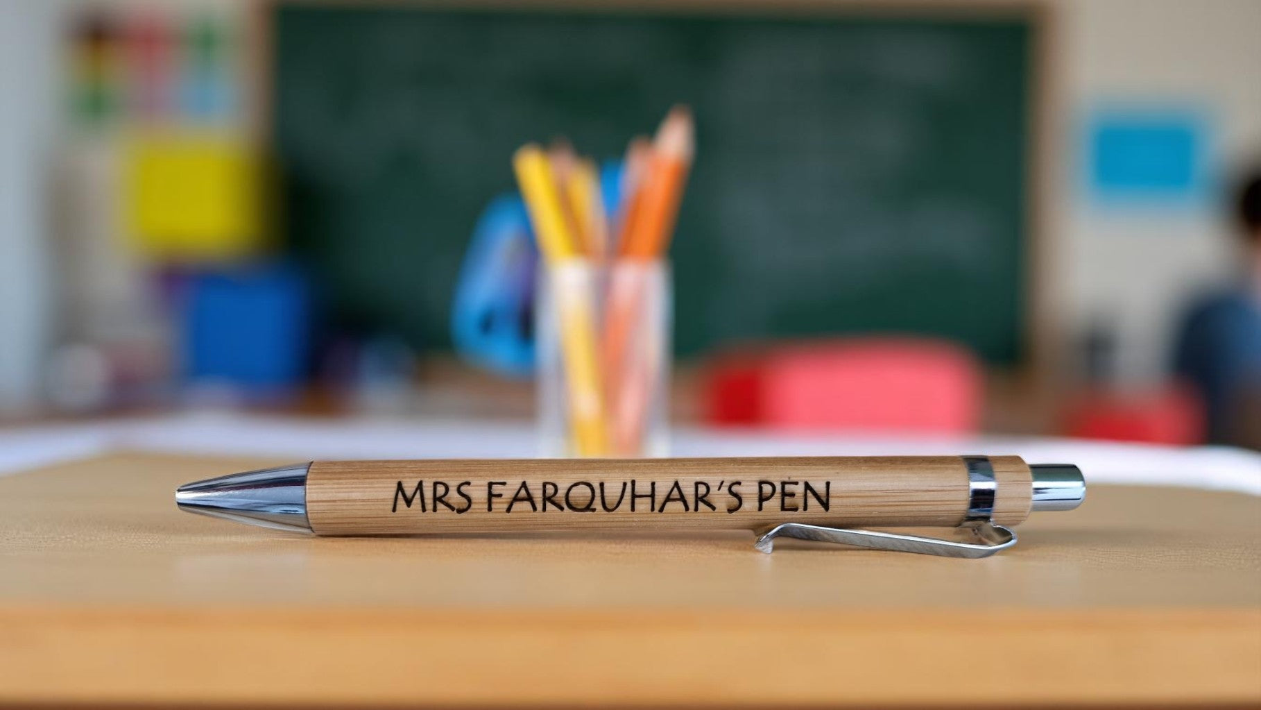 Personalised bamboo black pen engraved with teacher’s name, displayed on a notepad with eco-friendly packaging, ideal for gifts and stationery lovers