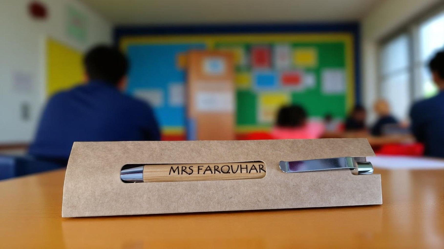 Personalised bamboo black pen engraved with teacher’s name, displayed on a notepad with eco-friendly packaging, ideal for gifts and stationery lovers