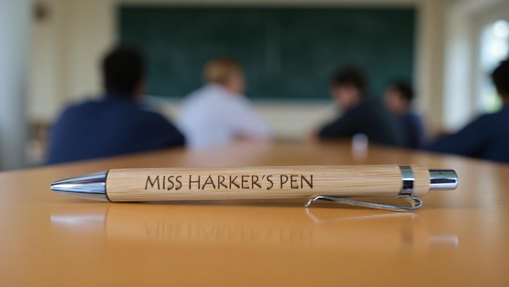 Personalised bamboo black pen engraved with teacher’s name, displayed on a notepad with eco-friendly packaging, ideal for gifts and stationery lovers