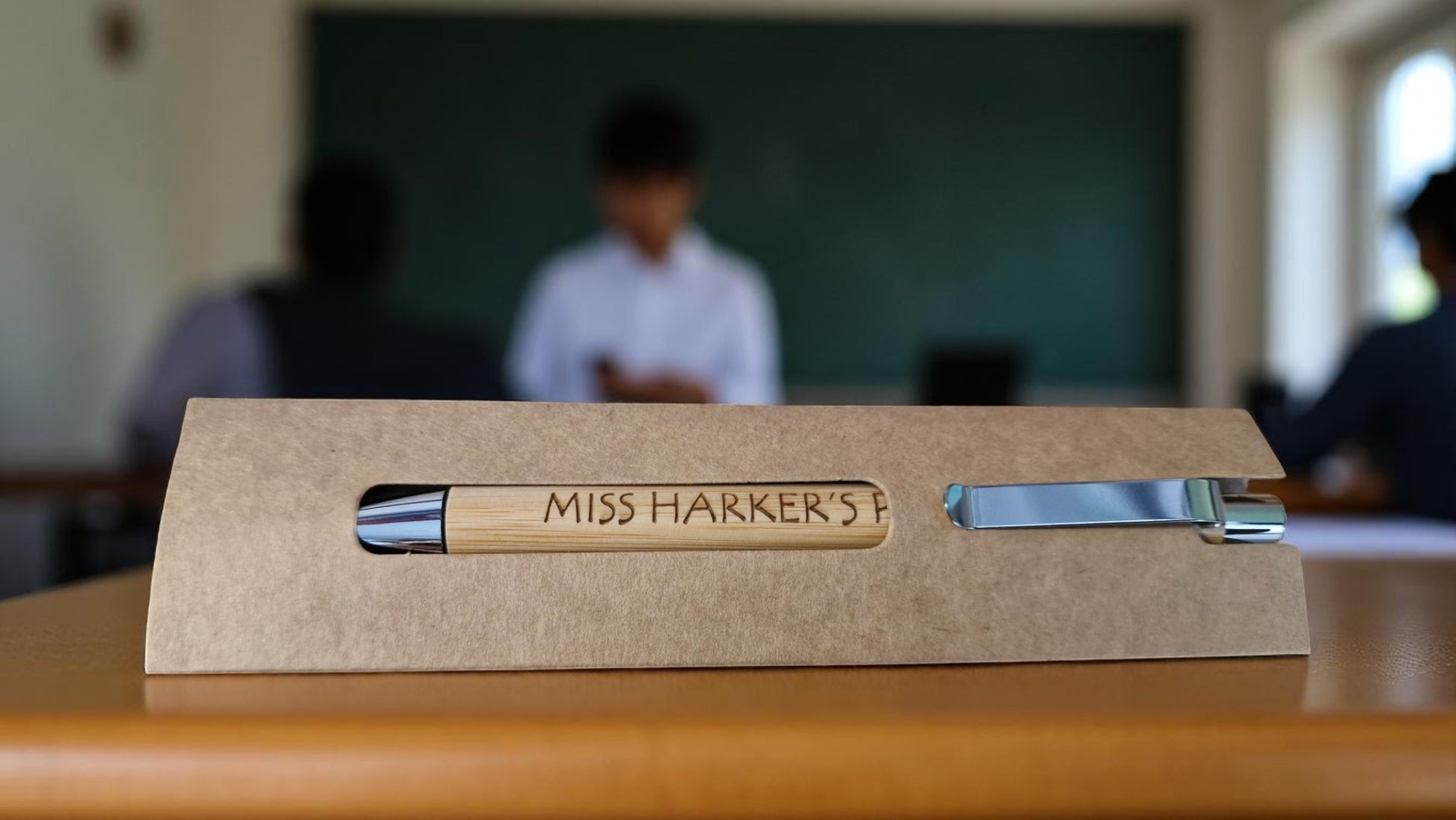 Personalised bamboo black pen engraved with teacher’s name, displayed on a notepad with eco-friendly packaging, ideal for gifts and stationery lovers