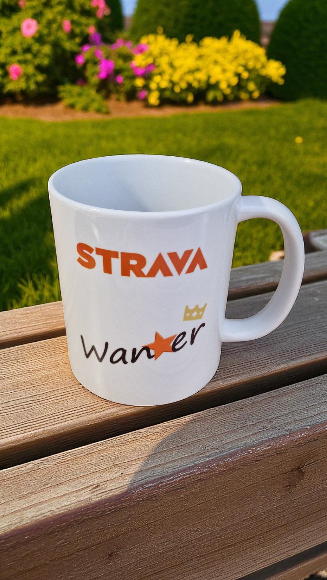 White mug with 'STRAYA' and 'Wander' text on a wooden surface with a garden background