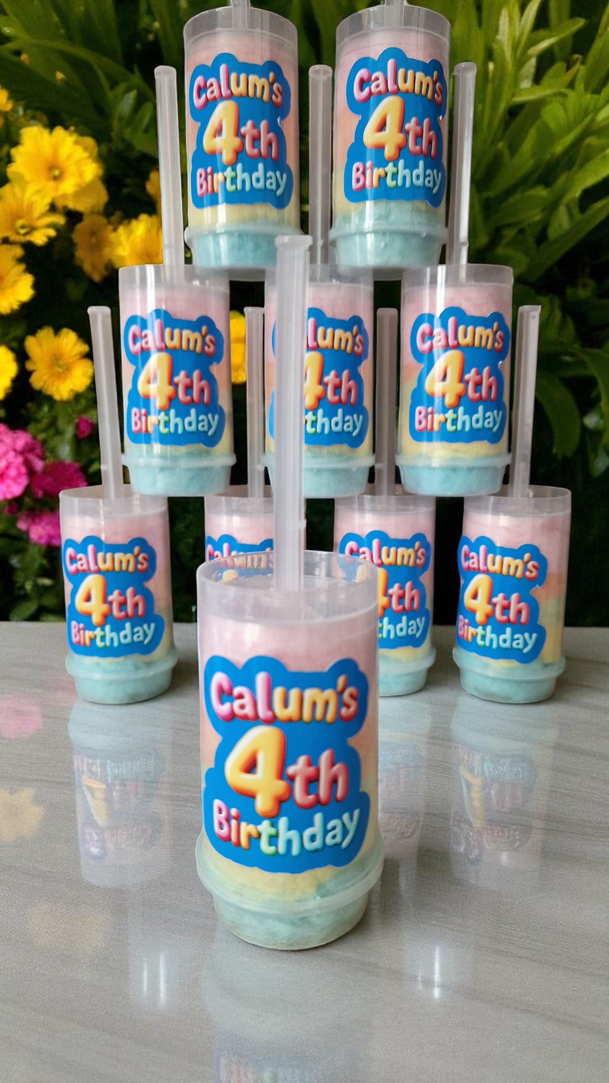 Ten personalised candy floss push pops in clear tubes with custom labels, displayed on a party table with colourful decorations—perfect for kids or adults