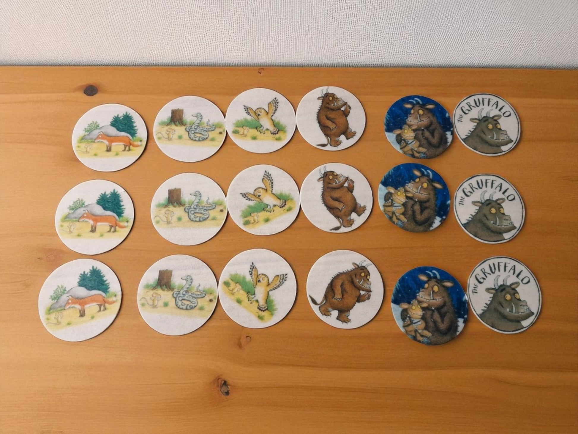 Gruffalo-themed cupcake case wrapper made of cardstock, featuring a colorful forest background with the Gruffalo character in the center, shown flat and unassembled on a wooden surface.