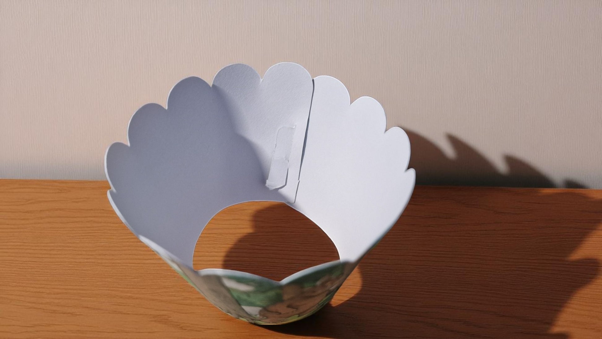 Gruffalo-themed cupcake case wrapper made of cardstock, featuring a colorful forest background with the Gruffalo character in the center, shown flat and unassembled on a wooden surface.