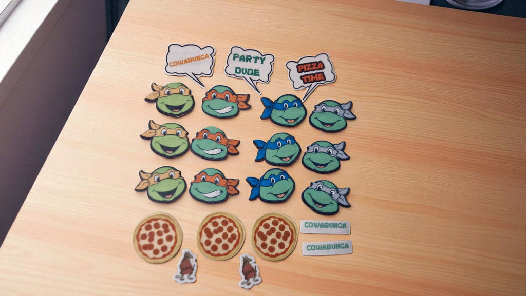 Set of cartoon turtle and fish figurines with speech bubbles and pizza slices on a wooden surface.