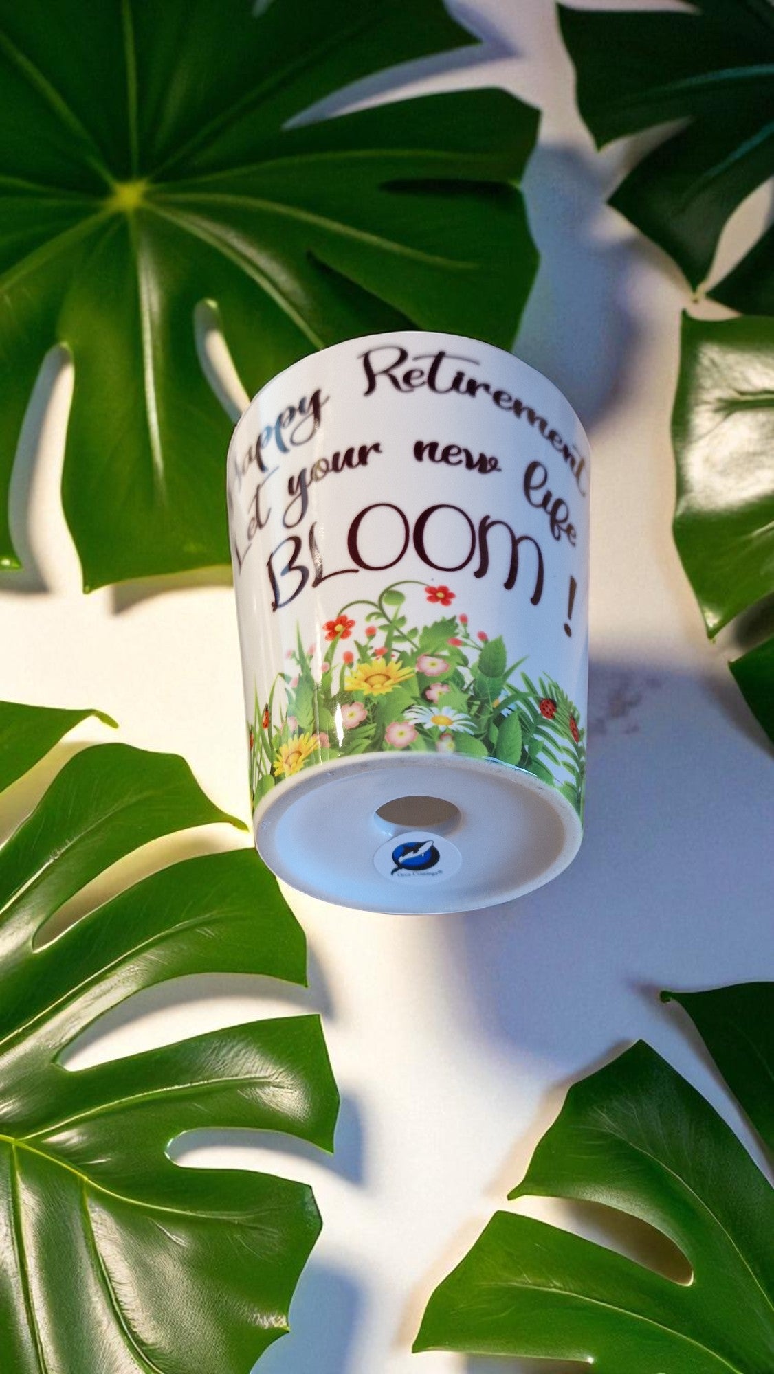 Ceramic planter with decorative text and flowers on a green leaf background