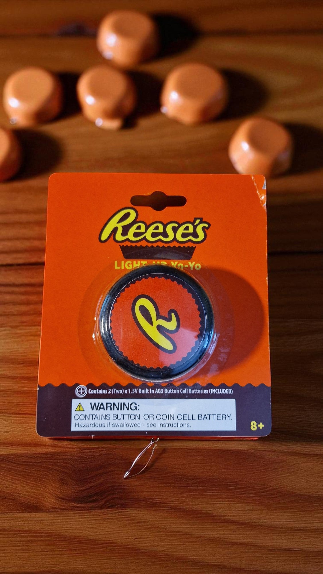 Front of Reese’s Light Up Yo-Yo in bright orange packaging, featuring Reese’s logo and yo-yo with yellow R, new in packaging, on a wooden table