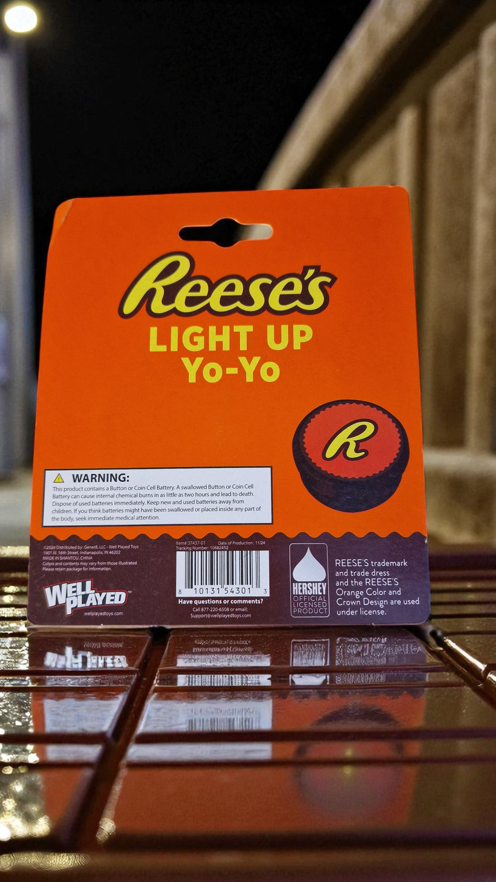 Front of Reese’s Light Up Yo-Yo in bright orange packaging, featuring Reese’s logo and yo-yo with yellow R, new in packaging, on a wooden table