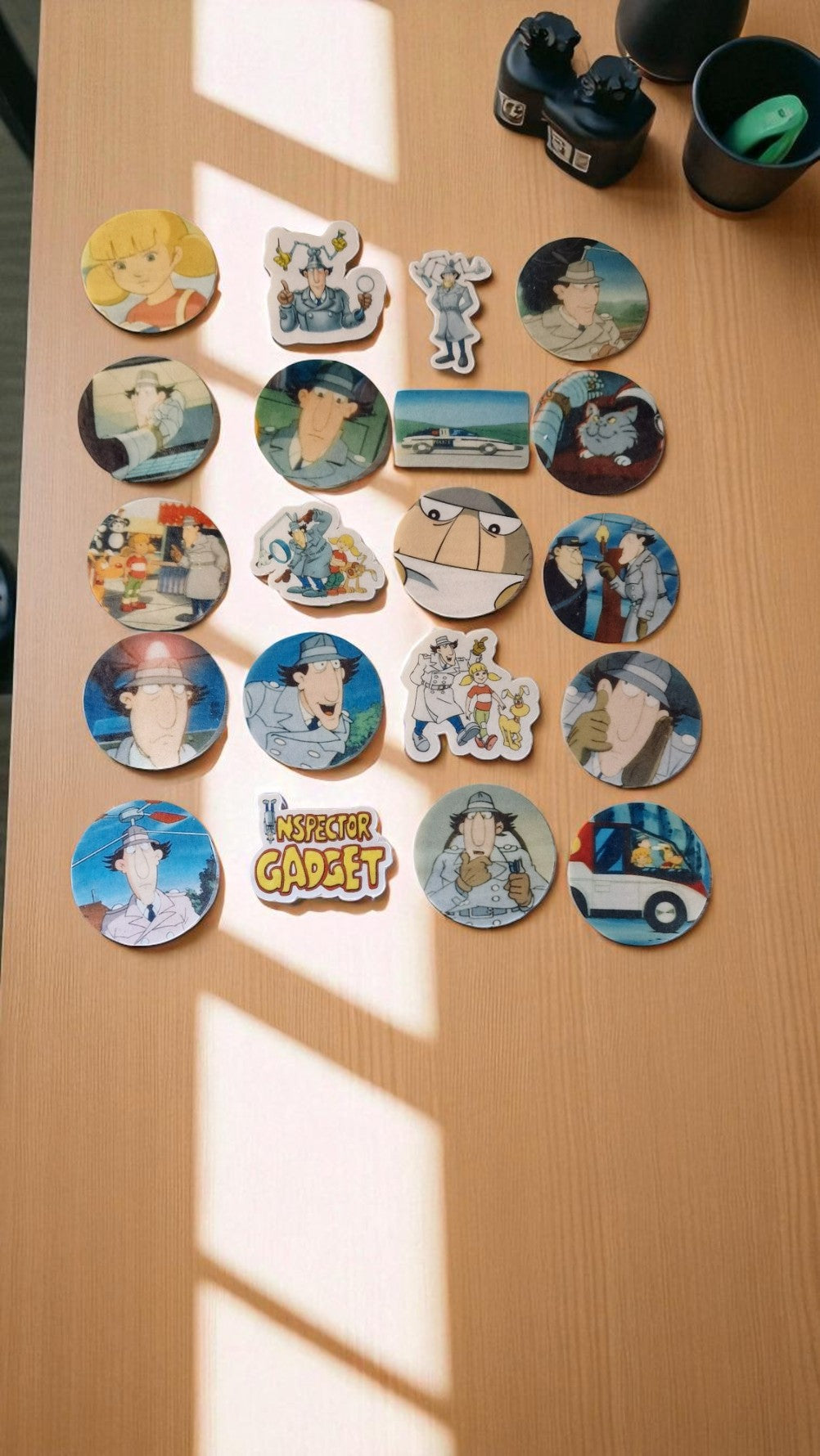 Collection of cartoon character pins on a wooden surface with 'My Little Garden' sign.