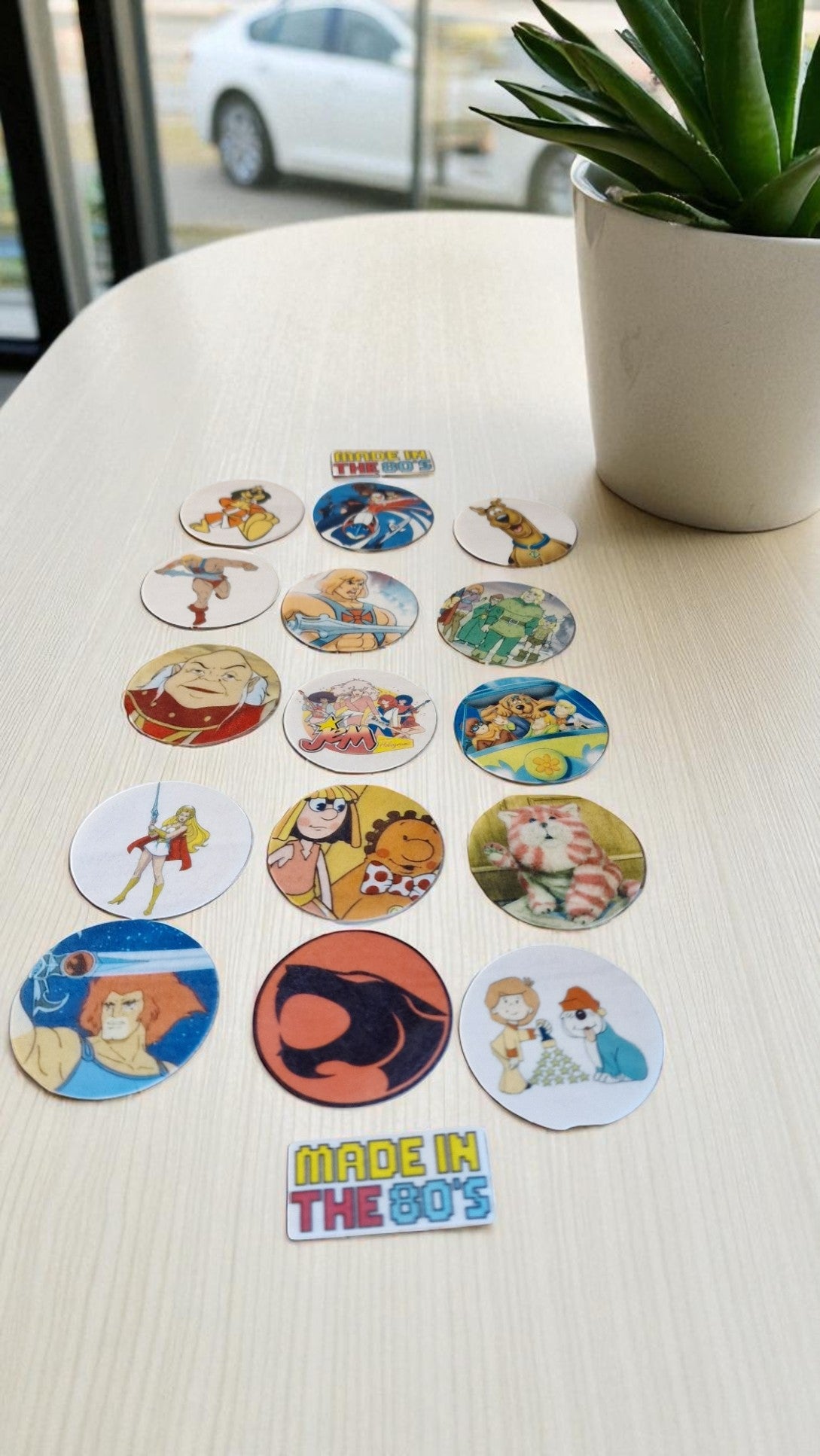 Collection of retro-themed stickers on a table with a plant in the background