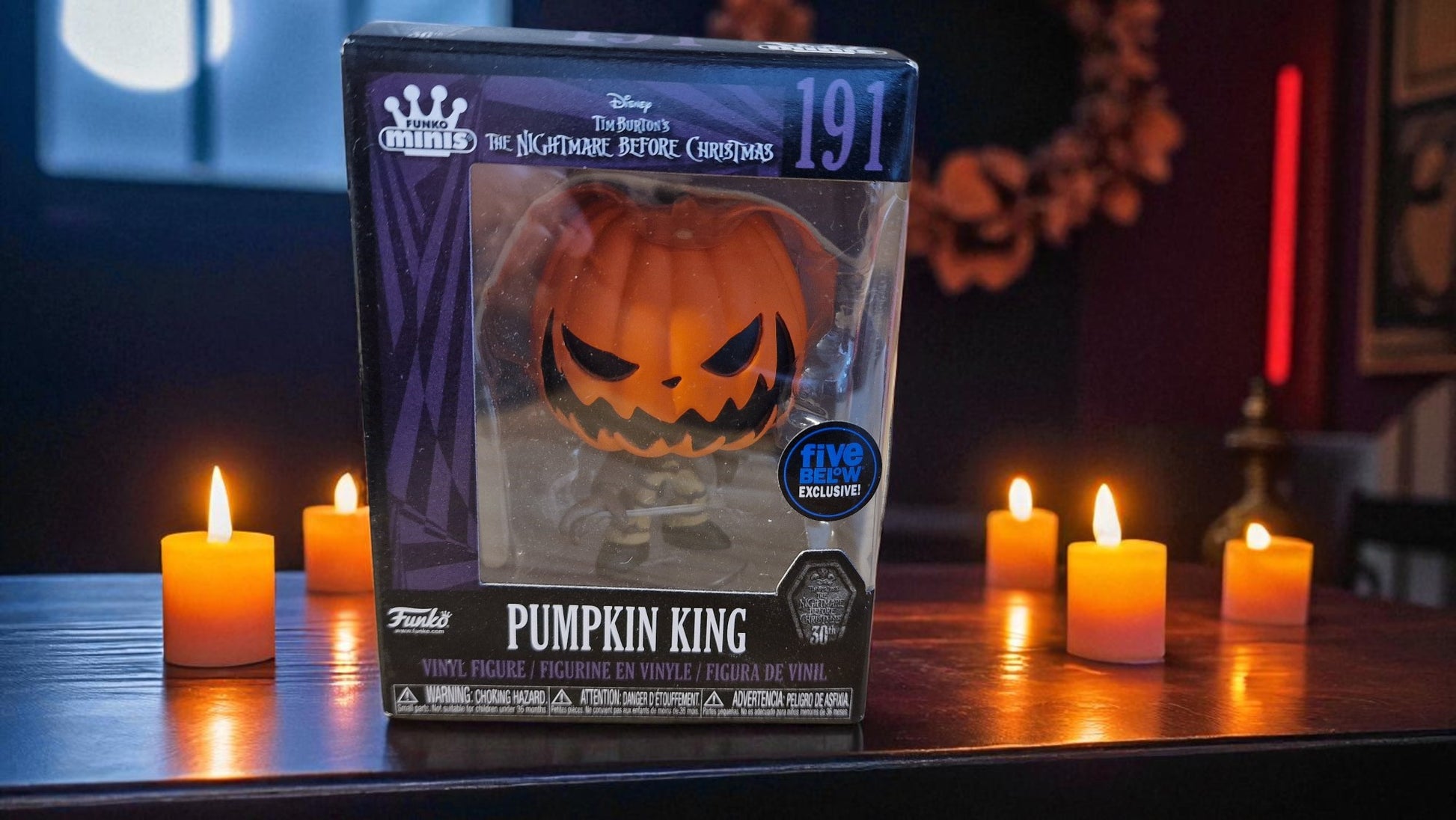 Pumpkin King toy figure packaging with candles on a table