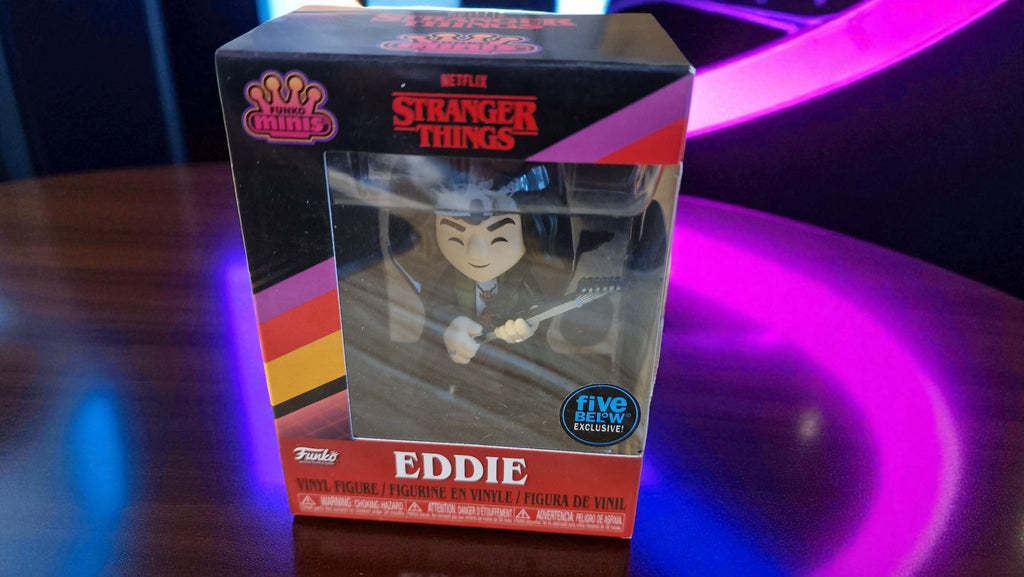 Stranger Things Eddie action figure in packaging on a reflective surface with purple lighting