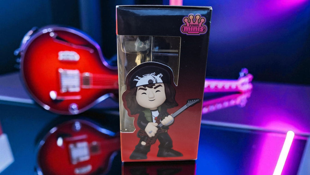 Boxed figurine with character design on a reflective surface with a guitar in the background