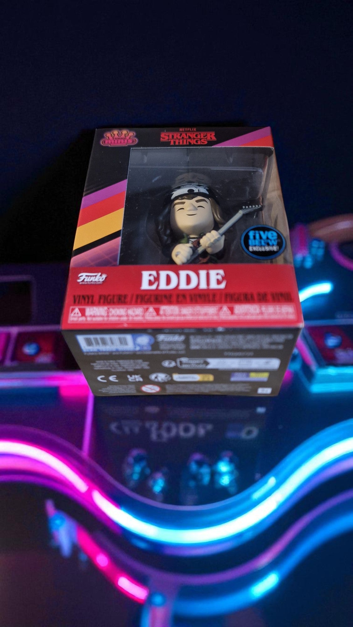Boxed figure of Eddie from Stranger Things with colorful neon lights in the background
