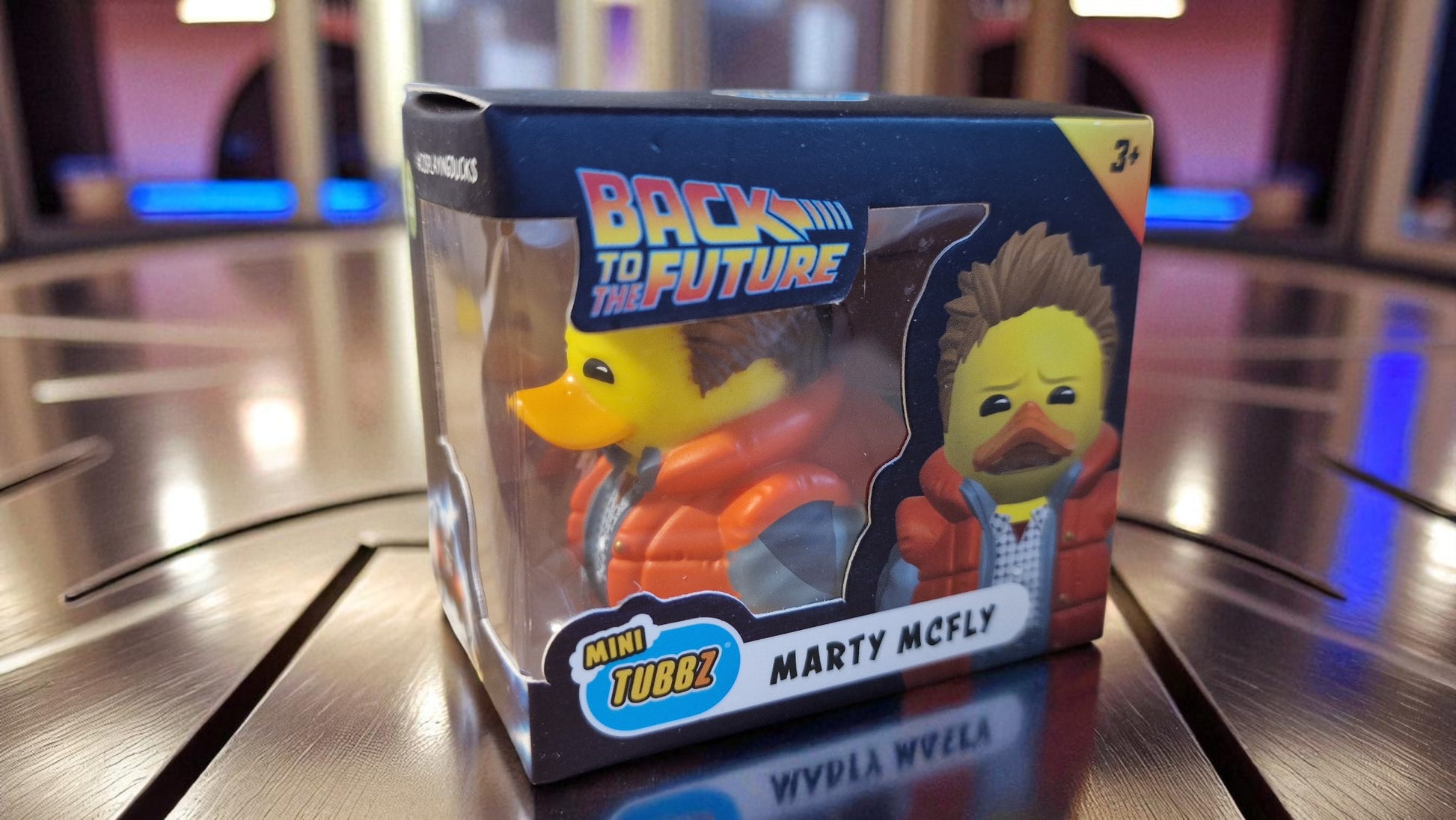 Toy figure of Marty McFly from 'Back to the Future' in packaging on a reflective surface.