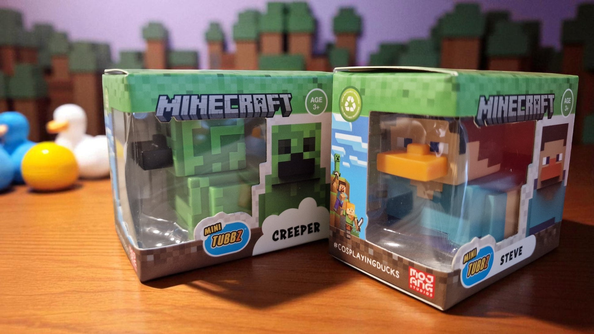 Two Minecraft figurine packages on a wooden surface with a colorful background.