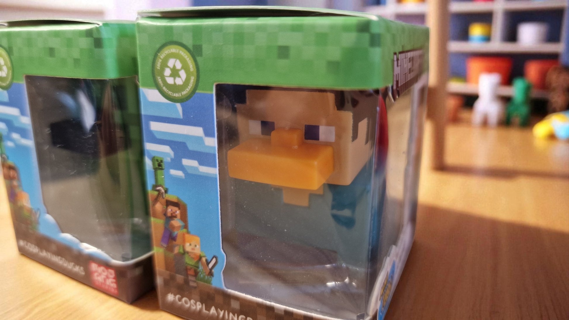 Toy figure in a transparent box with a green lid, displayed on a wooden surface.