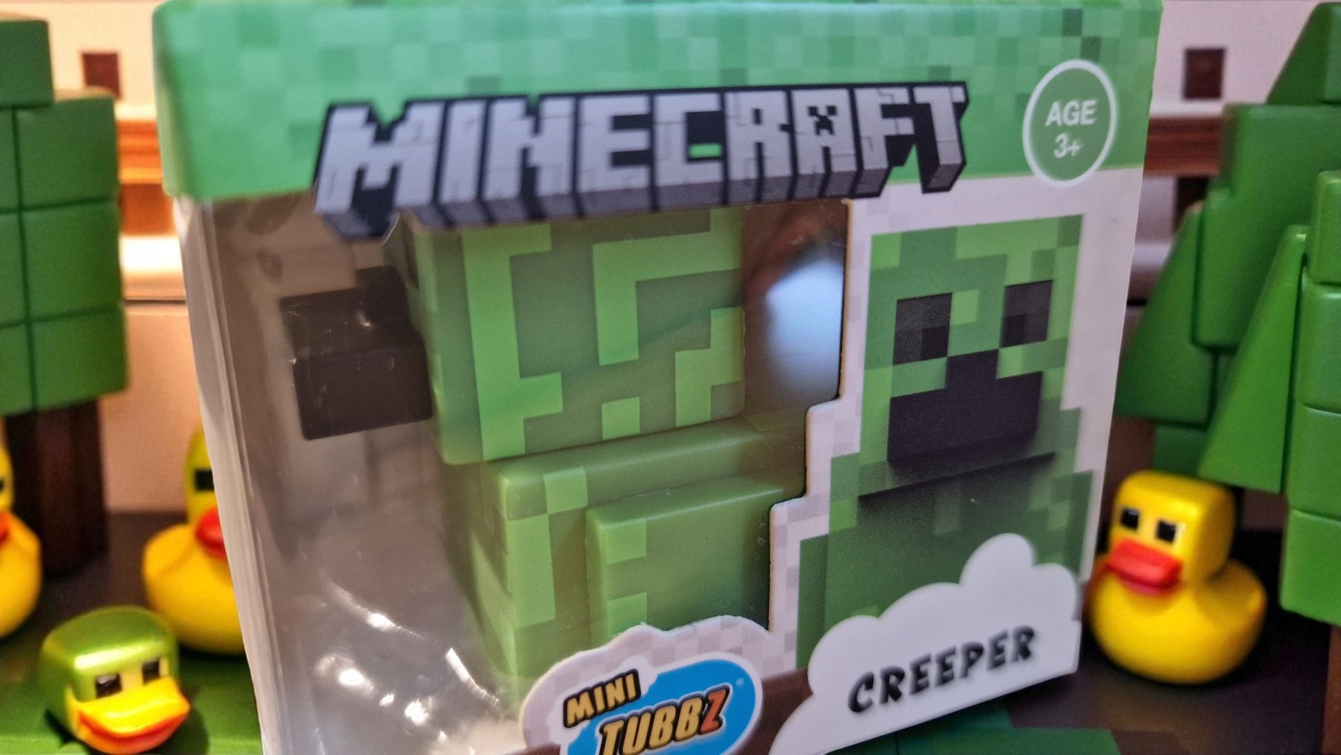 Minecraft Creeper figurine packaging with rubber ducks in the background