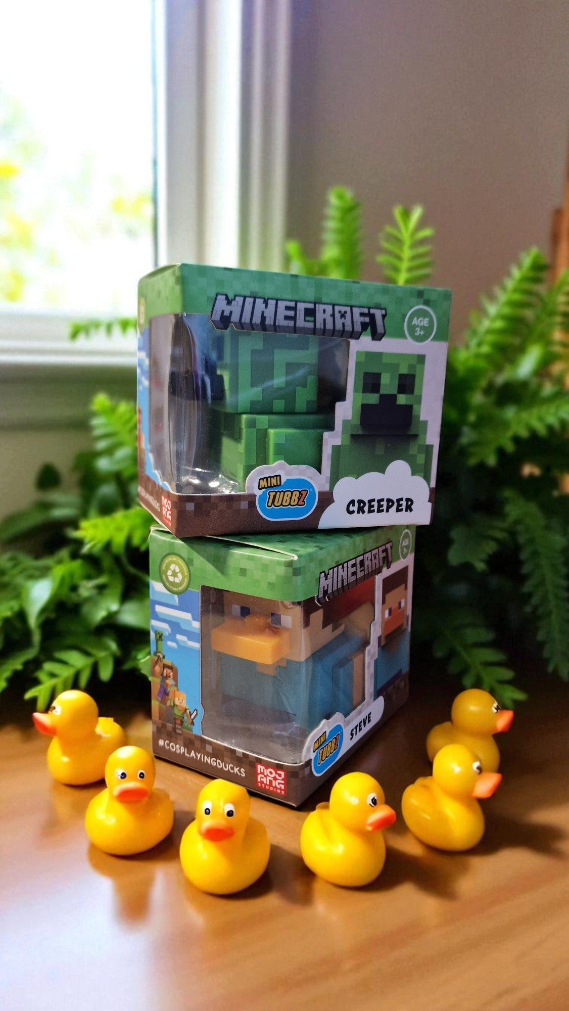 Stack of Minecraft toy boxes with yellow rubber ducks on a wooden surface.