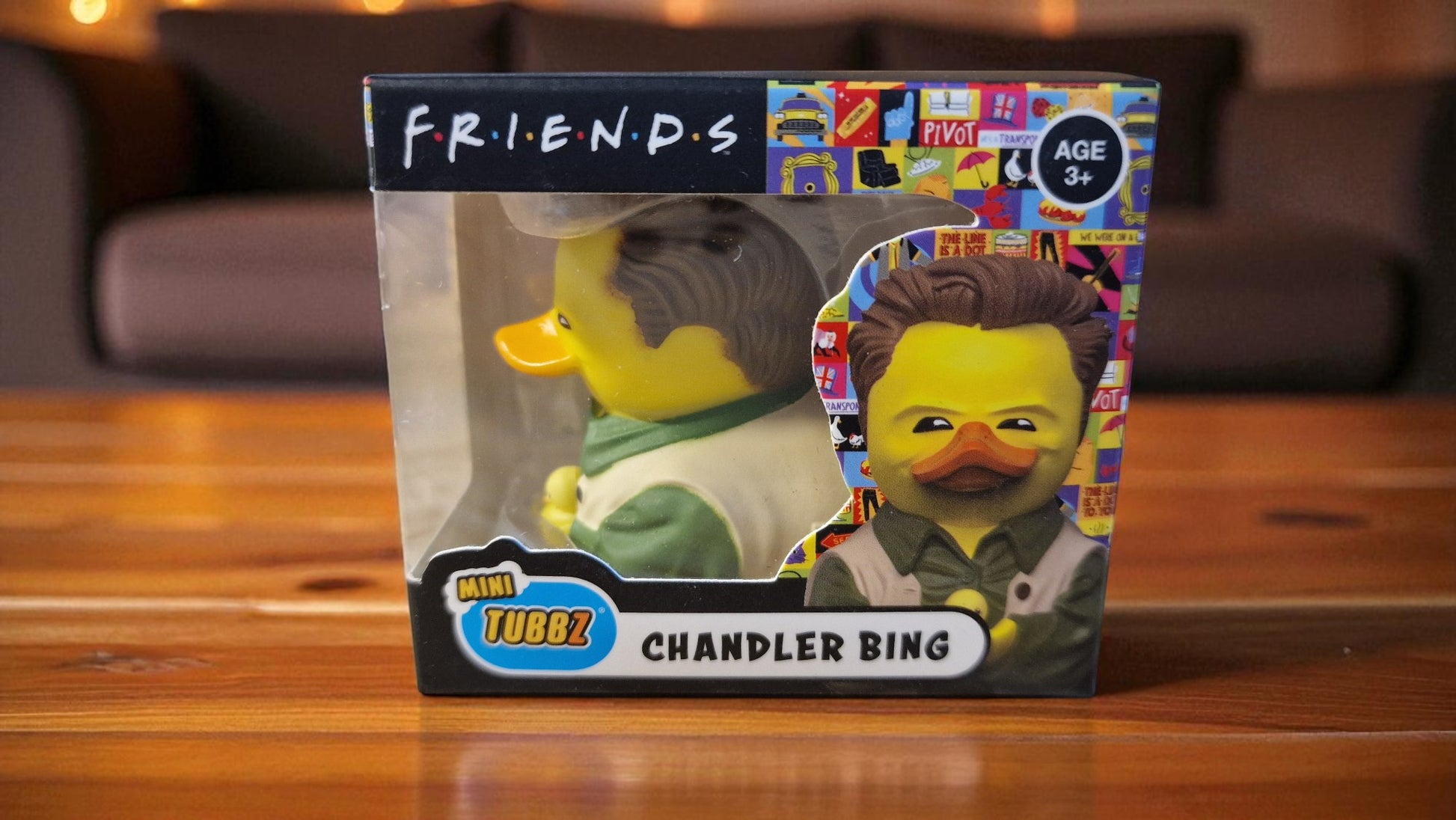 Toy figure packaging featuring characters from 'Friends' on a wooden surface.