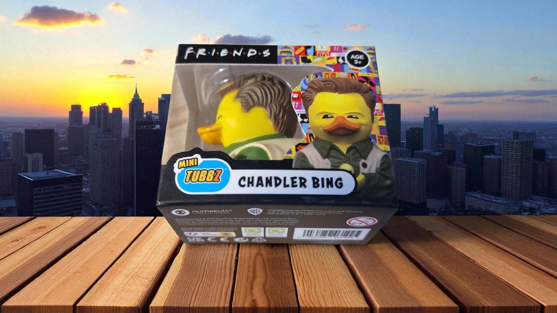 Toy figure of Chandler Bing from 'Friends' in a box with a cityscape background